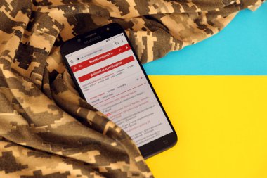 KYIV, UKRAINE - 4 Mayıs 2023: Ukrayna bayrağı ve kamuflaj kumaşı ile Ukrayna 'nın akıllı telefon ekranındaki muhabir Ukrayna haber portalı