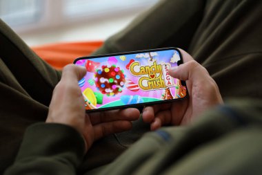 Candy Crush Saga mobil iOS oyunu iPhone 15 akıllı telefon ekranında oyun sırasında erkeklerin elinde. Taşınabilir aygıtta mobil oyun ve eğlence