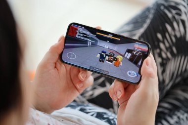 Roblox mobil iOS oyunu iPhone 15 akıllı telefon ekranında mobil oyun sırasında kadınların elinde. Taşınabilir aygıtta mobil oyun ve eğlence