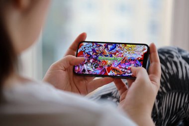 Canavar Vuruşu mobil iOS oyunu iPhone 15 akıllı telefon ekranında mobil oyun sırasında kadınların elinde. Taşınabilir aygıtta mobil oyun ve eğlence