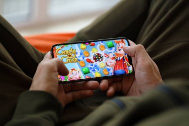 Candy Crush Saga mobil iOS oyunu iPhone 15 akıllı telefon ekranında oyun sırasında erkeklerin elinde. Taşınabilir aygıtta mobil oyun ve eğlence