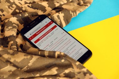 KYIV, UKRAINE - 4 Mayıs 2023: Ukrayna bayrağı ve kamuflaj kumaşı ile Ukrayna 'nın akıllı telefon ekranındaki muhabir Ukrayna haber portalı