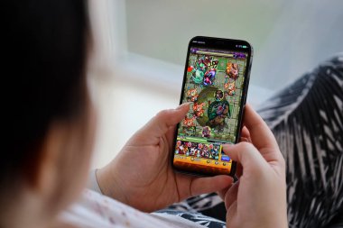 Canavar Vuruşu mobil iOS oyunu iPhone 15 akıllı telefon ekranında mobil oyun sırasında kadınların elinde. Taşınabilir aygıtta mobil oyun ve eğlence