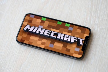 Minecraft mobil iOS oyunu iPhone 15 akıllı telefon ekranında ahşap masadaki mobil oyun sırasında. Taşınabilir aygıtta mobil oyun ve eğlence