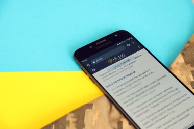 KYIV, UKRAINE - 4 Mayıs 2023: Ukr Net Ukrayna haber portalı Ukrayna bayrağı ve kamuflaj kumaşıyla akıllı telefon ekranında