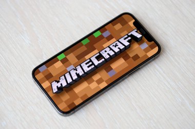 Minecraft mobil iOS oyunu iPhone 15 akıllı telefon ekranında ahşap masadaki mobil oyun sırasında. Taşınabilir aygıtta mobil oyun ve eğlence