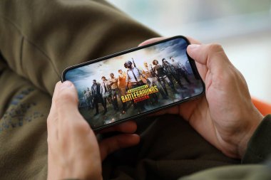 PUBG Bilinmeyen Oyuncular Battleground mobil iOS oyunu iPhone 15 akıllı telefon ekranında cep telefonu oyunu sırasında erkeklerin elinde. Taşınabilir aygıtta mobil oyun ve eğlence