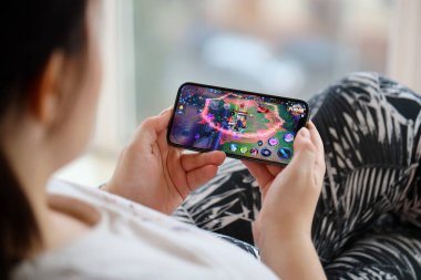 Mobil oyun sırasında iPhone 15 akıllı telefon ekranında kadınların elinde Kings 'in mobil iOS oyununun onuru. Taşınabilir aygıtta mobil oyun ve eğlence