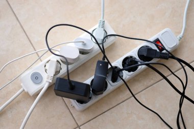 Aşırı yüklenmiş güç panoları. Beyaz zeminde farklı elektrik prizleri olan elektrik şeritleri. Risk tehlikesi kavramı elektrik akımını aşırı yükledi