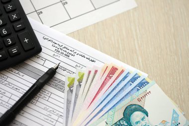 İran 'ın yıllık gelir vergi iade formu F20-25-006 kalem, hesap makinesi ve İran parasıyla doldurmaya hazır