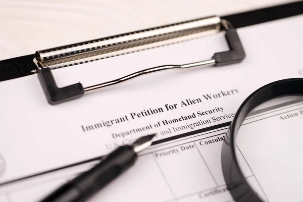 I-140 Immigrant petition for alien workers blank form on A4 tablet lies on office table with pen and magnifying glass close up