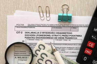 Kurumsal gelir vergisi mükellefleri tarafından kazanılan gelir miktarı veya zarar beyanı, muhasebeci masasının üzerindeki CIT-2 vergi formları, kalem ve cilalı zloti para faturaları kapanıyor