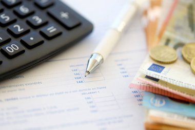 Fransızca vergi formunu hesap makinesi, kalem ve avro para faturalarıyla doldurmak. Vergi ödeme süresi ve son teslim tarihi