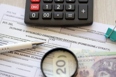 Kazanılan gelir veya zarar miktarının beyanı, muhasebe masasının üzerindeki PIT-36L vergi formları, kalem ve cilalı zloti para faturaları kapanır