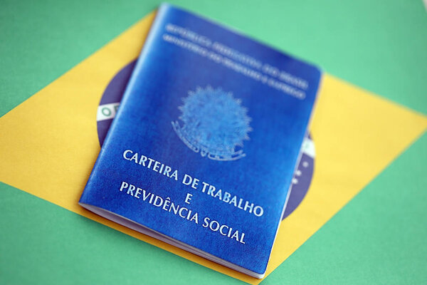 Brazilian work card and social security blue book on flag of Federative Republic of Brazil close up