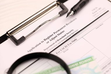 I-485 Kalıcı ikamet kaydı için başvuru formu veya A4 tabletindeki DV-lotoyu ayarlama yeşil kart, ofis masasında kalem ve büyüteçle kaplıdır