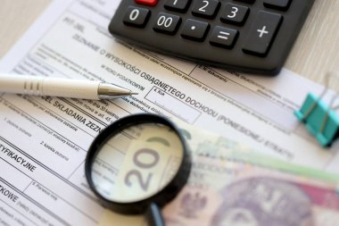 Kazanılan gelir veya zarar miktarının beyanı, muhasebe masasının üzerindeki PIT-36L vergi formları, kalem ve cilalı zloti para faturaları kapanır