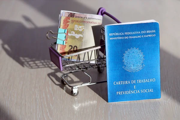 Brazilian work card and social security blue book and reais money bills in shopping cart close up
