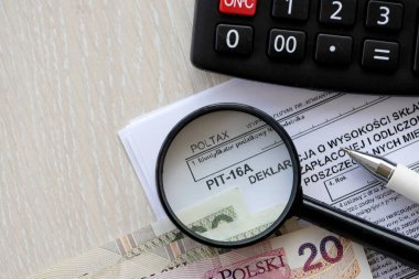 Vergi yılının bireysel aylarında ödenmiş ve vergi kartıyla ödenmiş sağlık sigortası katkı payı beyanı, kalem ve zloti para faturalarıyla dolu muhasebeci masasının PIT-16A formu