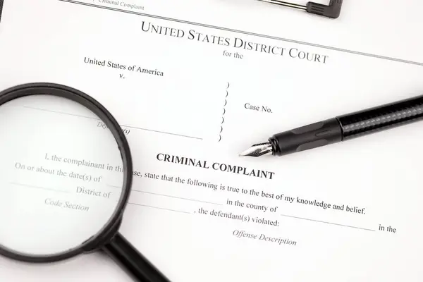 District Court Criminal complaint court papers on A4 tablet lies on office table with pen and magnifying glass close up