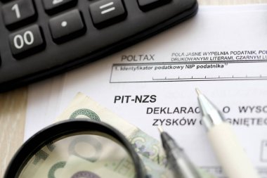 Girişim tarafından miras olarak elde edilen gerçekleşmemiş kar beyannamesi, tükenmez kalem ve cilalı zloti paraları ile muhasebeci masasının üzerindeki PIT-NZS formu