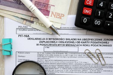 Vergi yılının bireysel aylarında ödenmiş ve vergi kartıyla ödenmiş sağlık sigortası katkı payı beyanı, kalem ve zloti para faturalarıyla dolu muhasebeci masasının PIT-16A formu