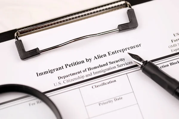 I-526 Immigrant Petition by Alien Entrepreneur blank form on A4 tablet lies on office table with pen and magnifying glass close up
