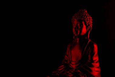 Buddha Purnima ve Vesak Günü konsepti, Kırmızı Buda heykeli, koyu siyah arka plana karşı alçak ışık altında yakın plan. Meditasyon