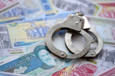İranlı para banknotlarıyla polis kelepçeleri. Suç, suç ya da dolandırıcılık kavramı