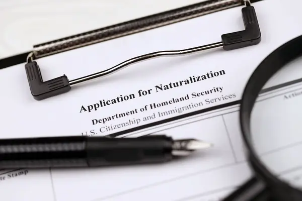 N-400 Application for Naturalization blank form on A4 tablet lies on office table with pen and magnifying glass close up