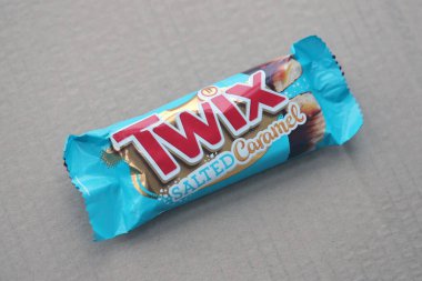 TERNOPİL, UKRAINE - 7 Temmuz 2023 Twix, ahşap zemin üzerinde tuzlu ve mavi karamel ambalajı. Twix, Mars Inc. 'in karamelli ve sütlü çikolatalı bisküvilerden oluşan bir çikolatadır.