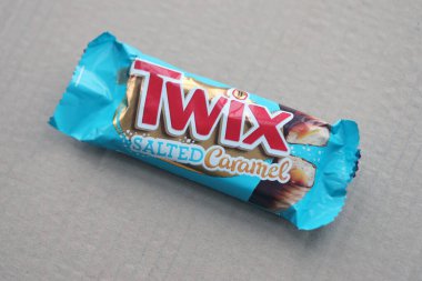 TERNOPİL, UKRAINE - 7 Temmuz 2023 Twix, ahşap zemin üzerinde tuzlu ve mavi karamel ambalajı. Twix, Mars Inc. 'in karamelli ve sütlü çikolatalı bisküvilerden oluşan bir çikolatadır.