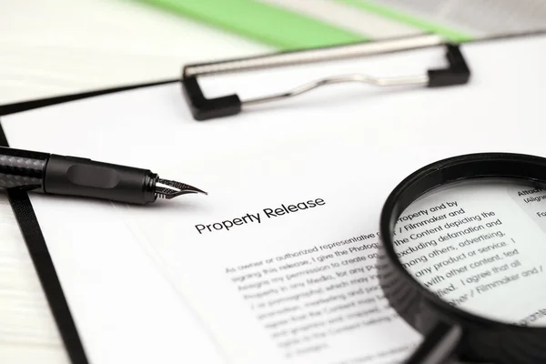 Property Release on A4 tablet lies on office table with pen and magnifying glass close up