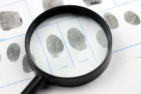 Fingerprints card police form on A4 tablet lies on office table with pen and magnifying glass close up