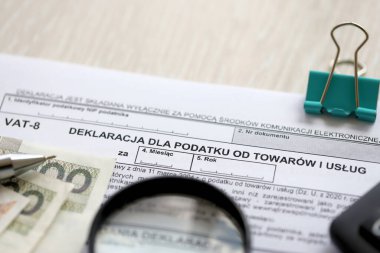 Mal ve hizmetlere uygulanan vergi beyannamesi. Muhasebeci masasında KDV-8 formu. Kalem ve zloti paraları kapatılacak.