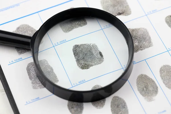 Fingerprints card police form on A4 tablet lies on office table with pen and magnifying glass close up