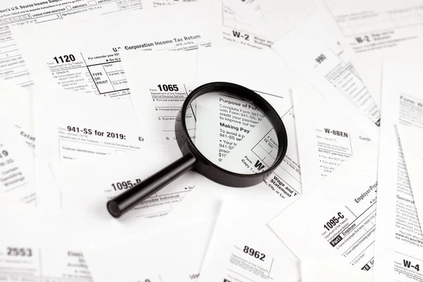 Magnifying glass lying over heap of paper documents. Investigation and financial audit concept