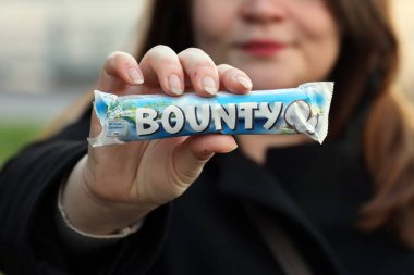 KYIV, UKRAINE - 31 Ekim 2023 Kadın elini dolduran kakao aromalı Bounty çikolataları. Bounty Çikolata, Amerikan Mars Şirketi 'nin bir markası.