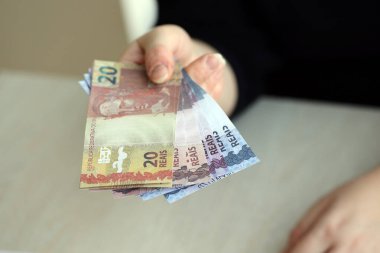 Brezilya 'nın para banknotları kadının elinde. Kadın bize Brezilya reais 'i veriyor. Yakından.