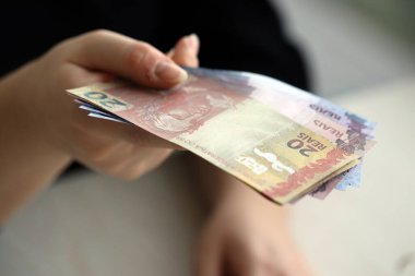 Brezilya 'nın para banknotları kadının elinde. Kadın bize Brezilya reais 'i veriyor. Yakından.