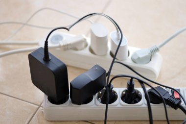 Aşırı yüklenmiş güç panoları. Beyaz zeminde farklı elektrik prizleri olan elektrik şeritleri. Risk tehlikesi kavramı elektrik akımını aşırı yükledi