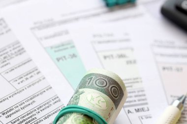 Kazanılan gelir veya zarar miktarının beyanı, PIT-36, PIT-36L, PIT-37 ve PIT-38 vergi formları muhasebeci masasında kalem ve cilalı zloti para faturalarıyla kapatıldı