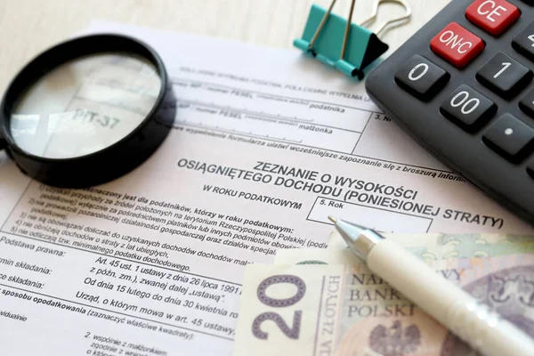 Kazanılan gelir ya da zarar miktarının beyanı, muhasebeci masasının üzerindeki PIT-37 vergi formları ve kalem ve zloti para faturalarının kapatılması