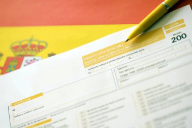 Modelo, vergi mükelleflerinin kurumsal gelir vergisi için 200 İspanyol vergi formu İspanya bayrağında muhasebeci masasına yakın duruyor.
