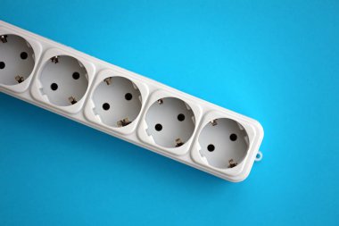 Parlak mavi arkaplanda Avrupa soketi olan beyaz elektrik çoklu priz genişleticisi