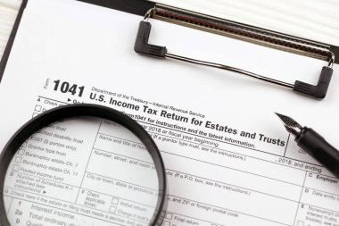 IRS Form 1041 US Income tax return for estates and trusts, blank on A4 tablet lies on office table with pen and magnifying glass close up clipart