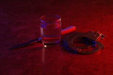 Votka alkollü bardak, bıçak ve kelepçe. Alkolizm, suç ve tutuklama kavramı