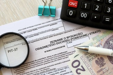 Kazanılan gelir ya da zarar miktarının beyanı, muhasebeci masasının üzerindeki PIT-37 vergi formları ve kalem ve zloti para faturalarının kapatılması