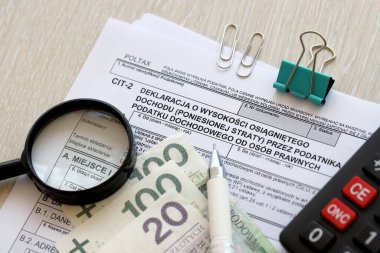 Kurumsal gelir vergisi mükellefleri tarafından kazanılan gelir miktarı veya zarar beyanı, muhasebeci masasının üzerindeki CIT-2 vergi formları, kalem ve cilalı zloti para faturaları kapanıyor