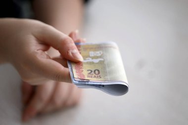 Brezilya 'nın para banknotları kadının elinde. Kadın bize Brezilya reais 'i veriyor. Yakından.